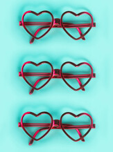 Close-up Of Pink Heart Shaped Eyeglasses Arranged On Blue Background