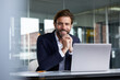 © Rainer Berg/Westend61 - Smiling businessman using laptop while sitting on chair in office