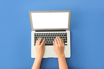Female hands with modern laptop on color background
