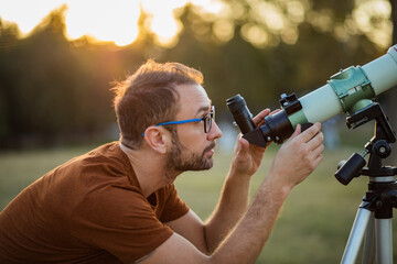 Wall Mural - amateur astronomer looking at the sky with a telescope.