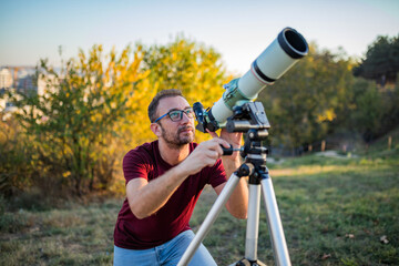 Wall Mural - amateur astronomer looking at the sky with a telescope.