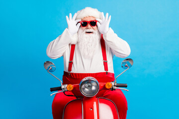 Wall Mural - Photo of funky modern santa claus drive motor bike x-mas christmas jolly party touch sunglass wear suspenders overalls cap isolated over blue color background