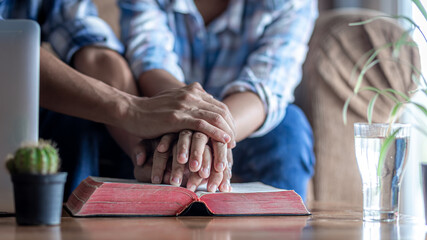 Close up hands praying of two person on Bible at home, church in home, Home church during quarantine coronavirus Covid-19, Religion concept.
