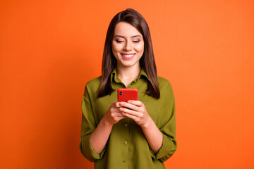Wall Mural - photo of cheerful lovely lady hold telephone look screen wear green shirt isolated orange color back