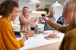 © Monkey Business - Group Of Mature Friends Making A Toast As They Meet At Home For Meal And Serve Food In Kitchen