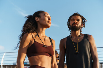 Young african american man and woman smiling while walking outdoors