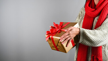 Female hands outstretched gift box with red ribbon, Isolated on grey, space for text.