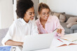 © Drobot Dean - Happy multicultural students girls using credit card while doing homework with laptop