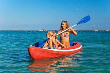 Wall Mural - Happy family - young mother, children have fun on boat walk. Woman and child paddling on kayak. Travel lifestyle, parents with kids recreational activity, watersports on summer sea beach vacation.