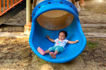 Wall Mural - Asian girl is enjoy on a playground equipment in a school.