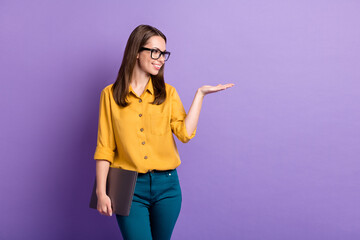 Poster - Photo of lovely girl hold netbook hand empty space look wear specs yellow shirt blue pants isolated purple color background