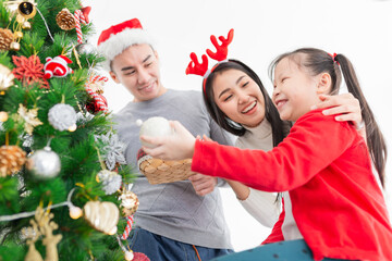 close up asian girl, asian family playing near Christmas tree in relax time, they decorate home, they feeling happy and smile, child development and family activity, celebration in Christmas season