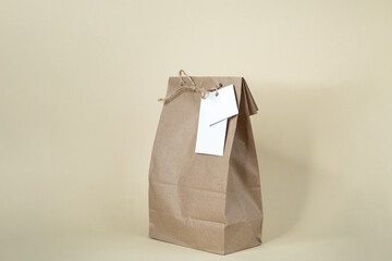 A gift bag made of craft paper of a neutral shade. Copy space. Mock up. Delivery or online shopping concept