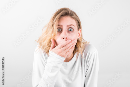 Portrait of a surprised beautiful girl covering her mouth with her hand in wow effect