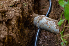 Sewer And Water Pipes In An Excavated Trench Deep In The Ground, Close Up. Sewerage And Water System Repair Concept.