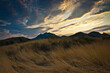 Faded grass in the forefront in windy weather and Echki-Dag mountain ridge beyond in Crimea. Colorful sky with stratocumulus clouds in the sunset..