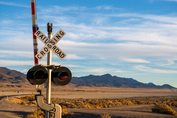Image of a railroad crossing at the intersection of a highway in a mountainous desert