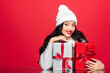 © LIGHTFIELD STUDIOS - happy woman in hat embracing christmas presents isolated on red