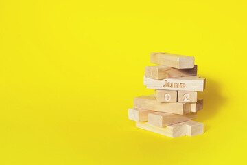 June 2nd. Day 2 of month, Calendar date. Wooden blocks folded into the tower with month and day on yellow background, with copy space. Summer month, day of the year concept.