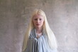 Medium horizontal natural light portrait of beautiful legally blind blue-eyed albino young girl draped in shawl looking straight ahead