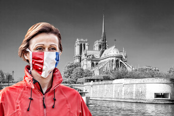 Fototapete - Woman wearing protection face mask with French flag against coronavirus near the Notre Dame cathedral with sunrise in France