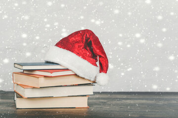 Merry Christmas.books and santa Claus hat on a wooden table.Christmas concept background
