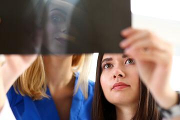 Group of beautiful female doctors hold in hand and look at xray photography to detect problem. Bone disease exam, medic assistance, cancer aid, healthy lifestyle, ill test, hospital practice concept