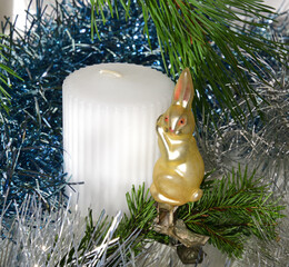 Vintage Christmas toy (Funny Hare) on background of pine and spruce branches and shiny tinsel