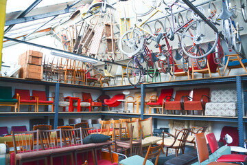 Vintage furniture shop. Second hand furniture market. Retro furniture for sale. Antique vintage store.  Old bikes hanging from ceiling.