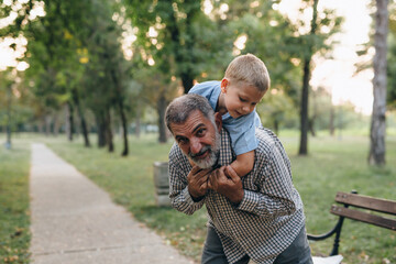 Wall Mural - grandfather carry piggyback his grandson in park