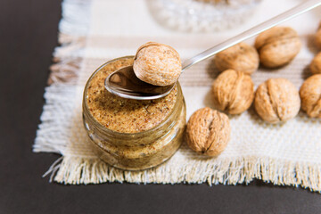 Glass jar of raw organic walnut butter or paste and fresh nuts in bowl