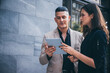 © chokniti - Two business people walking and discussing at the street outdoor by using the tablet for online report