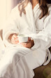 © julialototskaya - Girl holding a white coffee mug. In a white coat. Coffee in bed. Morning begins with coffee. Coffee in the hands of the bride