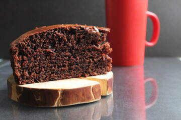 Canvas Print - chocolate brownie pie on a wooden stand log cabin back in the background is a red mug a Cup of tea coffee milk on a black background with a copy space for the text Breakfast dessert cafe tea coffee