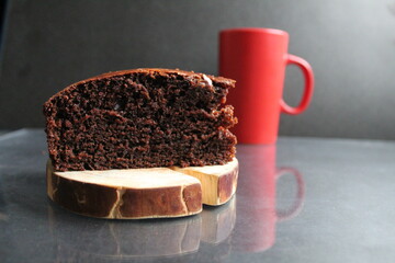 Canvas Print - chocolate brownie pie on a wooden stand log cabin back in the background is a red mug a Cup of tea coffee milk on a black background with a copy space for the text Breakfast dessert cafe tea coffee