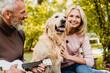 © InsideCreativeHouse - Cheerful mature caucasian couple spending time together with their dog while grey-haired man playing the ukulele in park