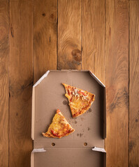 Ugly pizza pieces in pizza box on wooden surface