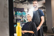 © LIGHTFIELD STUDIOS - cheerful hairdresser and smiling woman with hair wrapped in towel looking at camera, blurred foreground