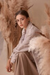 © Dmitry Tsvetkov - Fall fashion portrait. Brunette girl with pony tail and natural makeup. Elegant woman posing between ears of rye at textile background. Stylish female model in brown skirt anf beige jacket