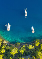 Wall Mural - aerial view to the three boats in emerald water and green forest on coastline