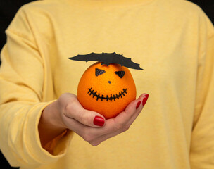 man holding a cheerful halloween orange with black bat