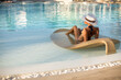 © abelena - Woman relaxing at the luxury poolside.
