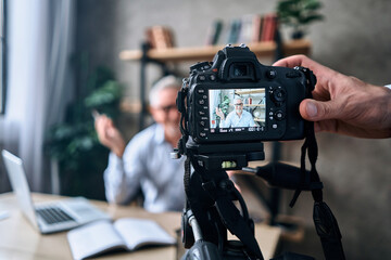 Smiling mature man telling about successful business strategies during recording video