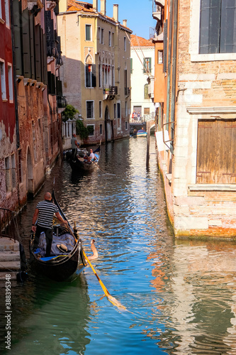 Gondolier and Tourists at Gondolas in Grand Canal with Traditional Venetian Colorful Houses - Quiet Morning in Venice, Veneto, Italy. © Bruno