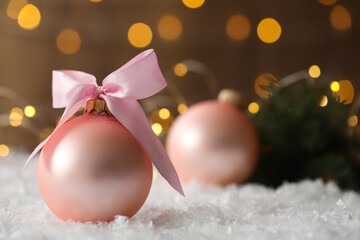 Beautiful Christmas ball on snow against blurred festive lights. Space for text