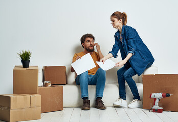 young couple on white couch with boxes of fun chatting