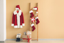 Costume Of Santa Claus With Christmas Gifts And Socks Near Color Wall