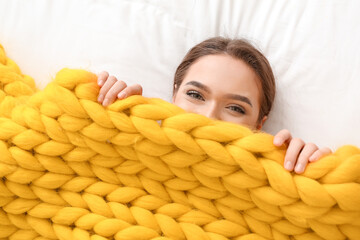 Poster - Happy young woman with warm plaid lying on bed, top view