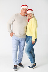 Poster - Mature couple in Santa hats on light background