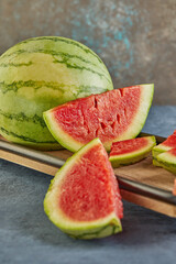 Poster - Mini Watermelon with sliced wedges on a wooden stand on a blue background